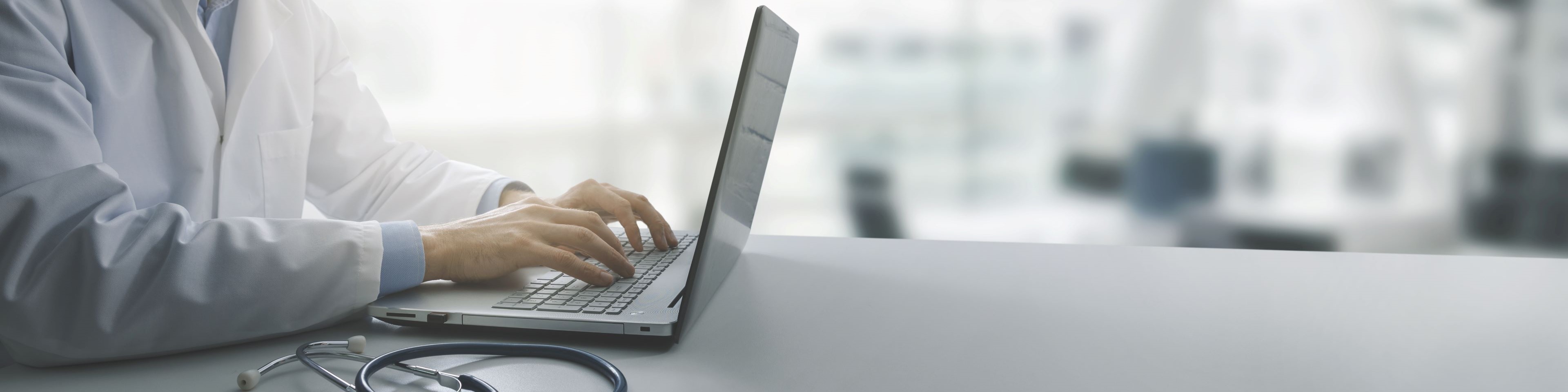 Doctor typing on laptop on desk. 