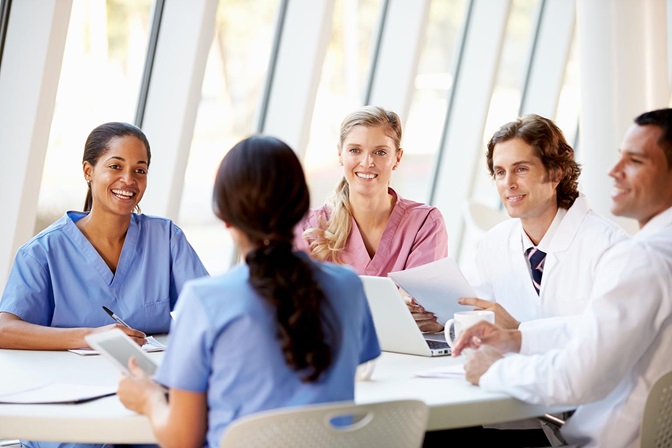 four woman medical professionals around laptop