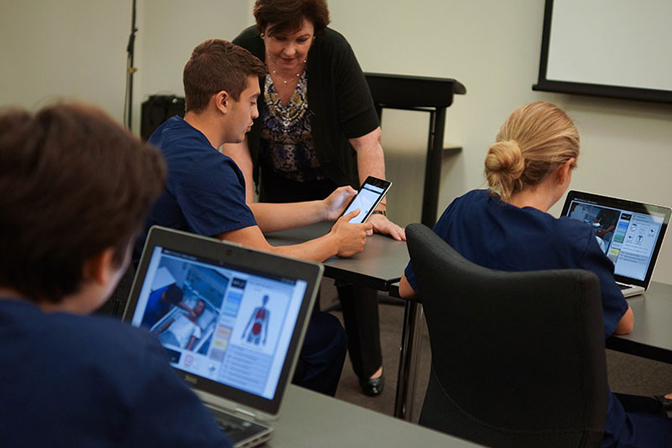Nursing students sitting down in classroom with vSim for Nursing on their mobile and laptops