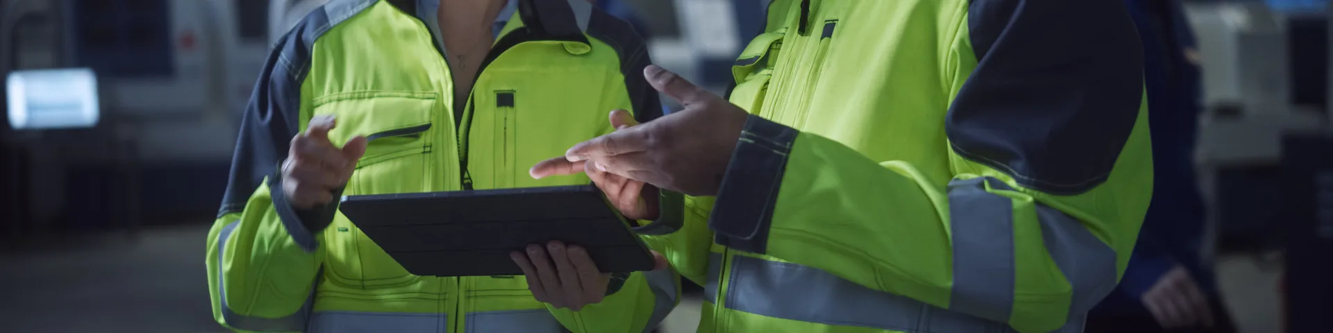 Chief Engineer and Project Manager Wearing Safety Vests and Hard Hats, Use Digital Tablet Computer in Modern Factory, Talking, Optimizing Production Line. Industrial Facility with CNC Machinery
